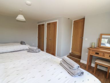 A bedroom with two beds with folded towels on them wooden doors and a wooden dressing table with a mirror at Curtau Llanfaredd near Builth Wells