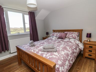 A bedroom with a wooden bed and bedside tables with lamps at Curtau in Llanfaredd near Builth Wells