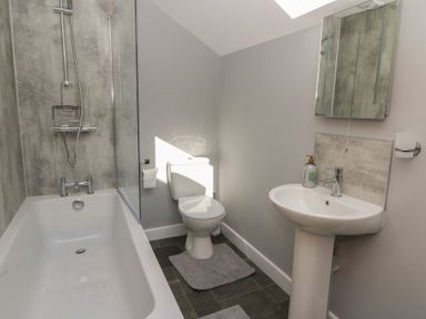 A bathroom with a bathtub shower combination toilet sink and mirror cabinet at Curtau in Llanfaredd near Builth Wells