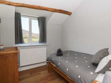 A small bedroom with a single bed and wooden chest of drawers at Curtau Llanfaredd near Builth Wells