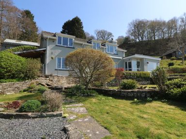 A house with a garden and stone wall in front of a hillside at Curtau in Llanfaredd near Builth Wells