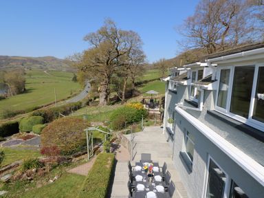 A patio with an outdoor dining table set next to a house overlooking a garden and countryside at Curtau in Llanfaredd near Builth Wells