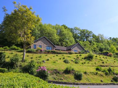 A stone house on a hillside with trees and bushes at Curtau Llanfaredd near Builth Wells