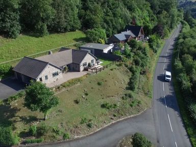An aerial view of two houses next to a road surrounded by trees and grass at Curtau in Llanfaredd near Builth Wells