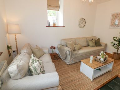 A living room with two beige sofas a wooden coffee table and a floor lamp at The Stables Near Solva