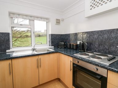 A kitchen with a window above a sink electric stove oven toaster kettle and containers at Time and Tide in Arnside