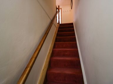 A carpeted staircase with wooden handrail and white walls at Time and Tide in Arnside