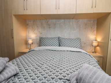 A bedroom with a bed with patterned bedding and pillows flanked by two lamps on bedside tables at Time and Tide in Arnside