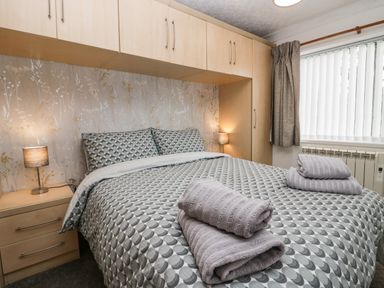 A bedroom with a bed covered in patterned bedding and folded towels on top at Time and Tide in Arnside