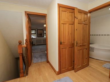 A hallway with wooden doors leading to a bathroom and a carpeted room at Time and Tide in Arnside