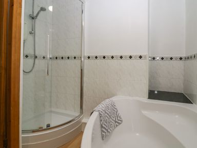 A bathroom with a corner shower enclosure and a bathtub with a towel on the edge at Time and Tide in Arnside