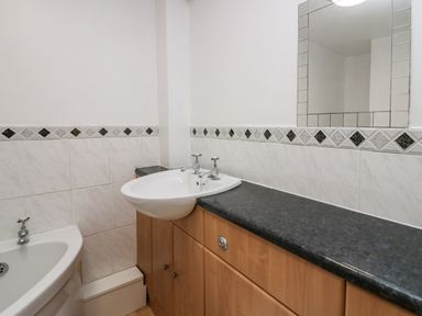 A bathroom with a sink, countertop, mirror, and bathtub with tiled walls at Time and Tide in Arnside