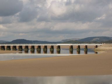 A bridge over water with sandbanks and hills in the background at Time and Tide in Arnside