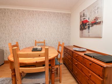 A dining room with a wooden table and chairs a wooden dresser and a painting on the wall at Time and Tide in Arnside