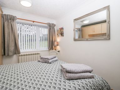 A bedroom with a bed covered in patterned bedding and folded towels on top at Time and Tide in Arnside