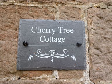 A stone plaque with Cherry Tree Cottage written on it attached to a stone wall at Cherry Tree Cottage in Fallodon near Embleton