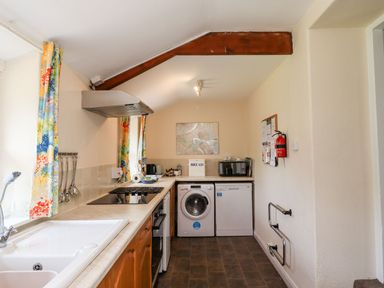 A kitchen with a sink stovetop oven washing machine and dishwasher at Cherry Tree Cottage in Fallodon near Embleton
