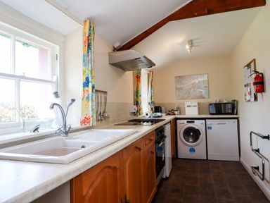 A kitchen with a sink stove oven washing machine dishwasher and microwave at Cherry Tree Cottage in Fallodon near Embleton