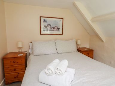 A bedroom with a bed and bedside tables with lamps at Cherry Tree Cottage in Fallodon near Embleton