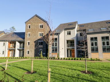 A modern residential building with stone and plaster exterior surrounded by grass and young trees at Brimstone in Backbarrow near Ulverston