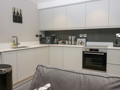 A kitchen with white cabinets oven microwave kettle and mugs at Brimstone Backbarrow near Ulverston