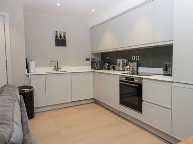 A modern kitchen with white cabinets a built-in oven a microwave kettle and toaster at Brimstone Backbarrow near Ulverston
