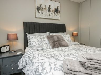 A bedroom with a bed with patterned bedding gray pillows and bedside tables with lamps at Brimstone Backbarrow near Ulverston