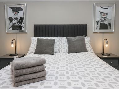 A bedroom with a double bed and two bedside tables with lamps and framed pictures at Brimstone Backbarrow near Ulverston
