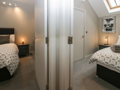 Two bedrooms separated by a wall each with a bed bedside table and lamp at Brimstone Backbarrow near Ulverston