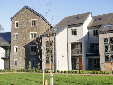 An apartment building with stone and white walls surrounded by grass and small trees at Brimstone Backbarrow near Ulverston