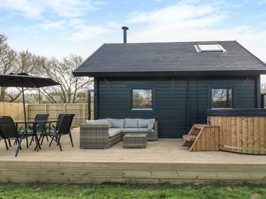 An outdoor patio with a table and chairs umbrella sofa and hot tub at Squirrel's Nest in South Luffenham near Edith Weston