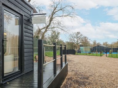 A wooden deck with a sign in front of a garden area at Squirrel's Nest in South Luffenham near Edith Weston