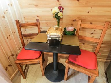 A small dining area with a black table and two wooden chairs with red cushions at The Poddy in Bushton near Lyneham