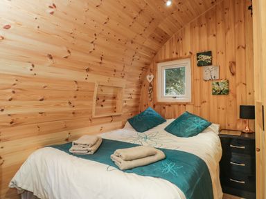 A bedroom with a bed towels bedside table and window at The Poddy in Bushton near Lyneham