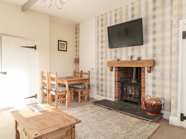 A living room with a wood stove fireplace a wooden dining table and chairs and a wooden coffee table at Moorlaws Farm in Alnwick