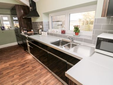 A kitchen with a countertop sink microwave and cabinets at Moorlaws Farm in Alnwick