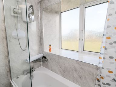 A bathroom with a bathtub shower combination and frosted window at Moorlaws Farm in Alnwick