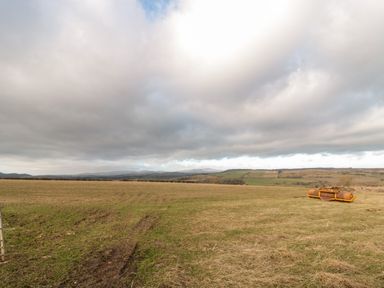 An open field with some tire tracks and a piece of orange machinery on the grass at Moorlaws Farm in Alnwick
