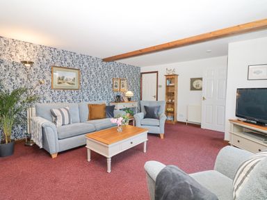 A living room with a sofa armchair coffee table and TV at Woodland View in Muddiford near West Down