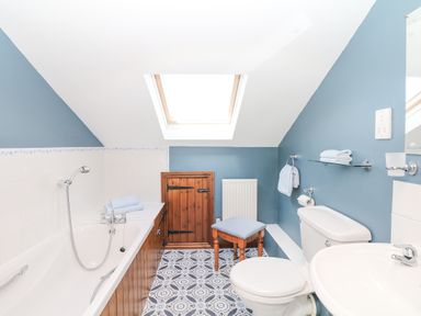 A bathroom with a bathtub toilet sink and wooden stool at Woodland View in Muddiford near West Down