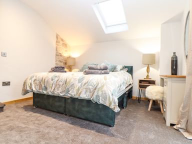 A bedroom with a bed with folded towels on it lamps on bedside tables a skylight and a small stool at La Petit Maison in St Columb Major