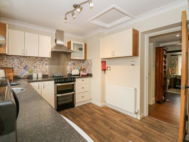 A kitchen with white cabinets a stove toaster and knives on the counter at Easter Cottage in Dersingham