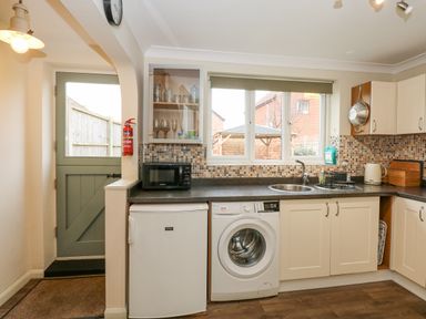A kitchen with a washing machine refrigerator microwave sink and various kitchen utensils at Easter Cottage in Dersingham