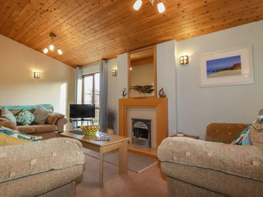 A living room with sofas a coffee table a television and a fireplace at 4 The Glade in St Minver