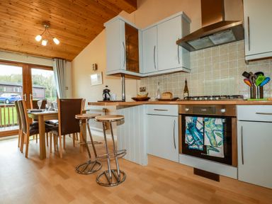 A kitchen with dining table wooden stools and oven at 4 The Glade in St Minver