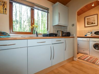 A kitchen with a window above the sink flowers on the windowsill white cabinets and appliances in a utility area at 4 The Glade in St Minver