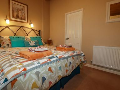A bedroom with a double bed with patterned bedding and folded towels on the bed at 4 The Glade in St Minver