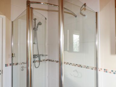 A bathroom shower enclosure with glass doors and tiled walls at 4 The Glade in St Minver