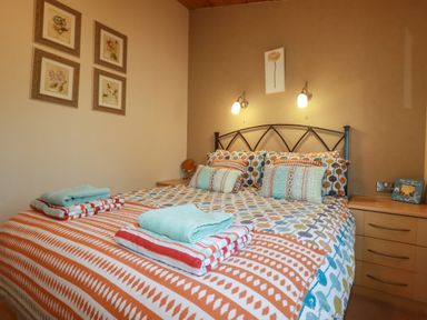 A bedroom with a patterned bedspread and pillows and folded towels on the bed at 4 The Glade in St Minver
