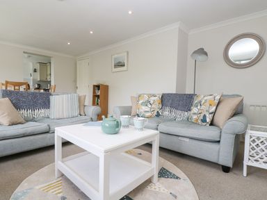 A living room with two sofas a white coffee table and a floor lamp at Godrevy in Porthcurno